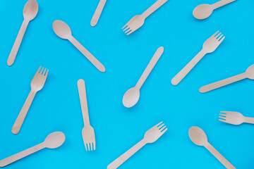 Texture of disposable bamboo spoons and forks on blue background. Zero waste concept. Top view, flat lay.