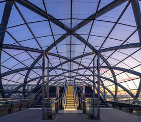 Modern train station glas roof and escalator at blue hour