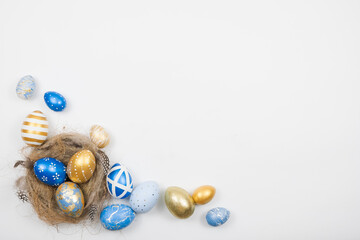 Easter golden blue decorated eggs in nest isolated on white background for web banner. Minimal easter concept. Happy Easter card with copy space for text. Top view, flatlay.