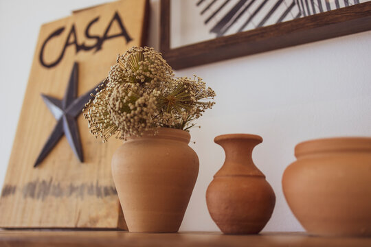 Modern luxury summer holiday or vacation beach house interior decoration. Ceramic clay pot vases on a shelf and an out of focus plaque with a metal starfish statue and the word "casa".