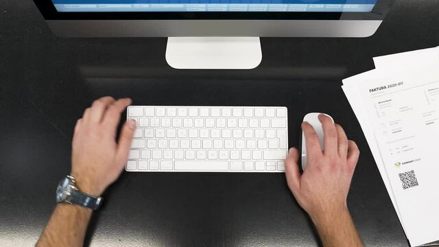 Male hands working on a modern PC,typing,clicking,pushing away papers.
