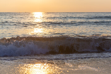 Yellow sunset from the low sun. Seashore with a sunset path on the waves.