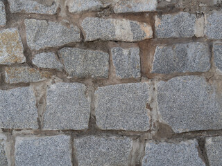 The texture of a rough medieval wall made of uneven cobblestones. The paving stone pattern. Old rock background made of different sized stones.