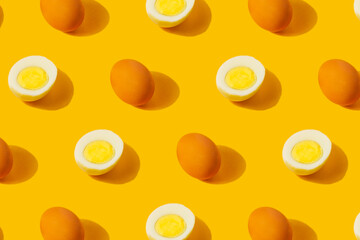 Farm chicken fresh and boiled half cut eggs pattern on yellow background. Healthy food or Happy Easter creative minimal concept. Flat lay, top view