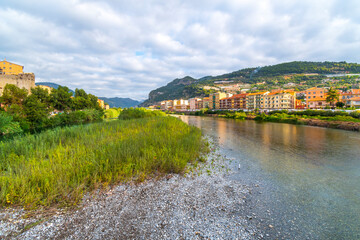 Fototapeta na wymiar View from the bridge across the river Roya of the village of Ventimiglia, Italy, and inland to the mountains of the Imperia region.