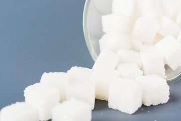 White sugar cube sweet food ingredient spilled out of the glass, studio shot isolated on a gray background, Minimal health high blood risk of diabetes and calorie intake concept