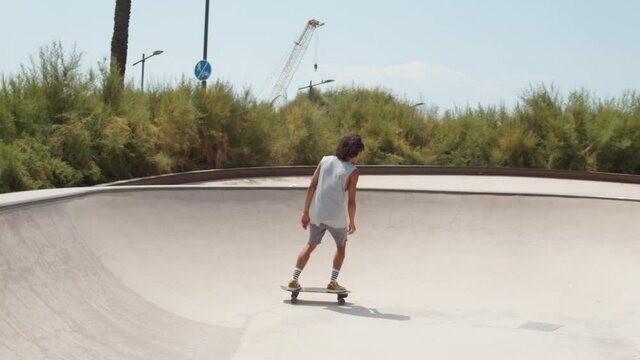 Professional skater in bowl skatepark doing tricks, skateboarder carving a turn in a deep concrete bowl, latin hispanic man on extreme surfboard, summer sports