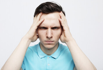 Naklejka premium Young handsome man wearing casual blue t-shirt over white isolated background with hand on head for pain in head because stress.