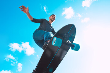 Skateboarder in action, making trick. Man riding on a skateboard outdoors on sunny summer day. Summer sport. Blue sky background. © Creative Cat Studio