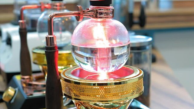 Beautiful coffee americano makes a barista in a gabe siphon in a cafe close-up, general plan
