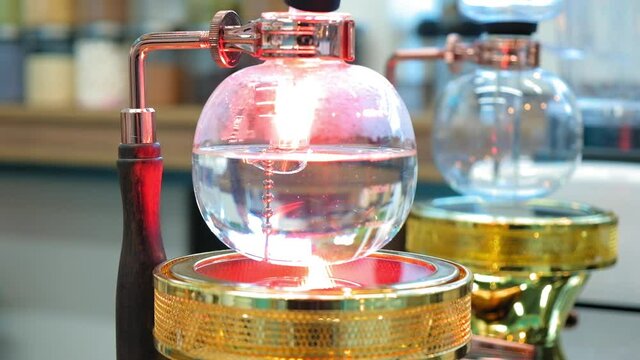 Beautiful coffee americano makes a barista in a gabe siphon in a cafe close-up, general plan