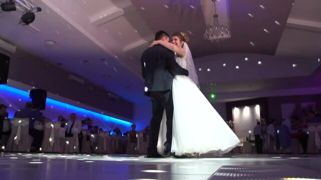 Groom holds bride carefully dancing in the restaurant. First dance bride. Happy bride and groom and their first dance, wedding in the elegant restaurant with a wonderful light and atmosphere