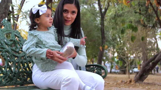 Madre arr&eacute;ala a su hija en parque sentada en una banca