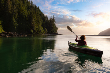 Adventurous Girl kayaking in the Pacific Ocean. Sunset Sky Art Render. Taken in San Josef Bay, Cape Scott, Northern Vancouver Island, British Columbia, Canada. Adventure Travel Concept