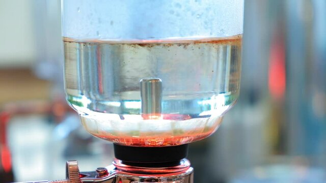Beautiful coffee americano makes a barista in a gabe siphon in a cafe close-up, general plan