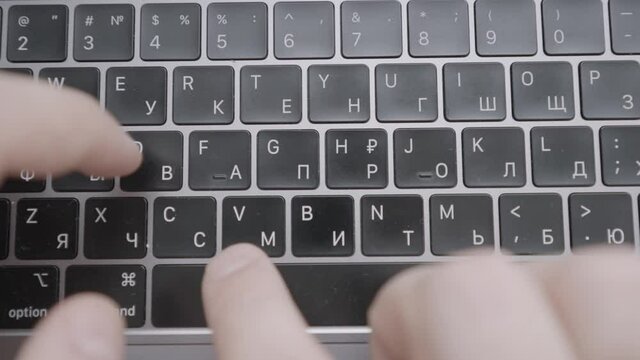 The man is texting quickly with his hands on a black keyboard with an English-Russian layout. Action. A man writes a letter or a message on on keyboard of a computer or laptop.