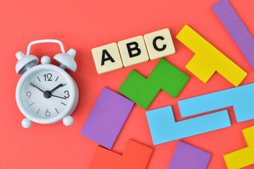 Clock, wooden blocks and alphabet letters over red background.
