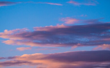 This image showcases whimsical fluffy sunset clouds in a bright blue sky