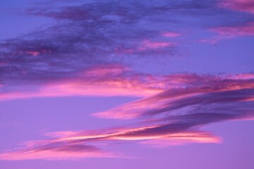 This image features an idyllic calm sky filled with pink and purple clouds illuminated by a stunning sunset.