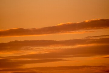 This photograph showcases idyllic clouds in an orange sunset sky.