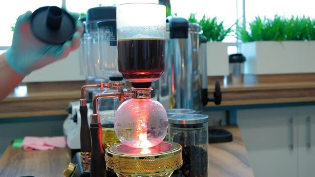 Beautiful coffee americano makes a barista in a gabe siphon in a cafe close-up, general plan
