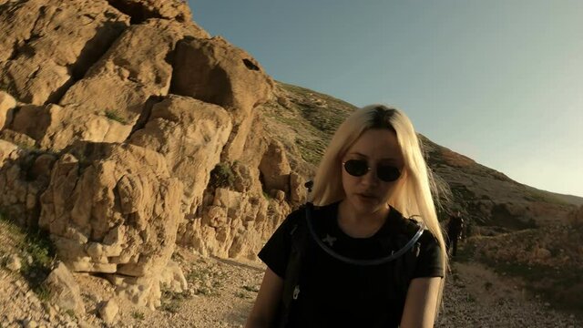 young blonde takes pictures of herself on a hike in the mountains, travel blog, and memories. High-quality 4k footage