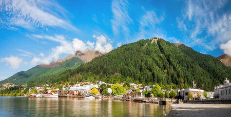 Panoramic view of the alpine city of Queenstown in New Zealand, from the marina bay of Lake Wakatipu with the Queenstown Skyline mountain in the background.