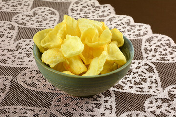 Veal and adjika flavored potato chips in ceramic snack bowl on pink heart table runner on brown tablecloth