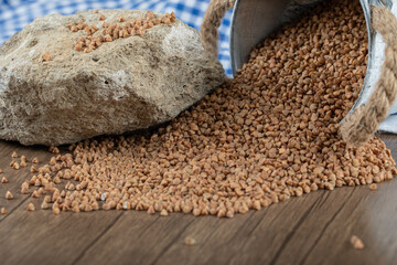 Uncooked buckwheat out of metal bucket on wooden table