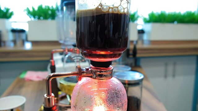 Beautiful coffee americano makes a barista in a gabe siphon in a cafe close-up, general plan