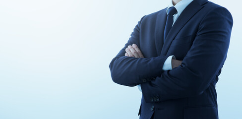 Businessperson looking confident with crossed arms. Pale blue background with copy space.