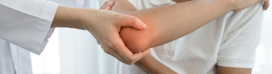 Female physiotherapists provide assistance to male patients with elbow injuries examine patients in...