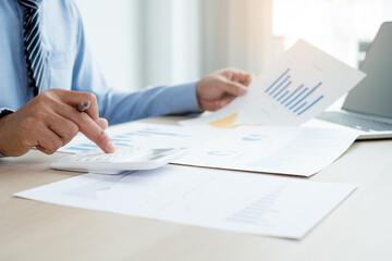The businessman's hand sits at their desks and calculates financial graphs showing results about their investments, plan a successful business growth process