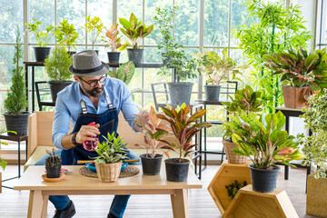 An elderly man handsome have mustache beard enjoys caring for his plants, watering, spraying, and decorating the plants. It is a hobby of gardening at home, living happily after retirement