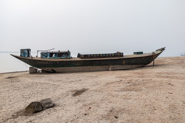 Obraz premium Wooden fishing boat on the beach with foggy sky.