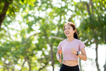 Beautiful young healthy Asian woman running in the park in the morning. Health care concept.
