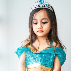 Portrait of a little girl dressed in arabian princess costume against white background. Natural light, selective focus.