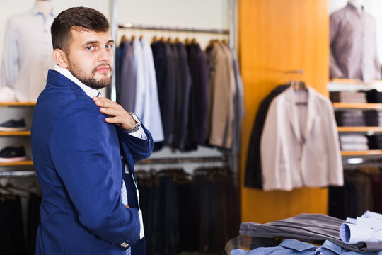 young man shows off his jacket at a men's store
