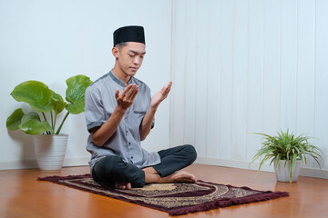 Young Asian muslim man pray on the prayer rug
