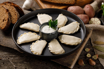 Appetizing traditional Russian dumplings, hand-made with potatoes. Still life on a wooden board. Close-up.