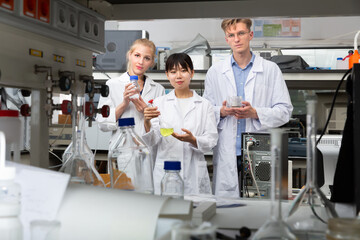 Obraz premium Glad male and female scientists in white coats posing at biochemical laboratory