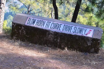 Blow horn at curve drive slowly sign outside the road in Himachal Pradesh India