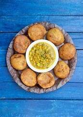 Top View of Khasta Kachori with Curried Yellow Peas or Ghugni Curry in a Leaf Plate Isolated  Blue Wooden Background, Indian Delicious Snack or Breakfast Food, Also Known as Kachodi 