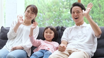 ソファに座って手を振る親子