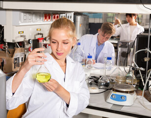 Portrait of European female scientist holding flask of reagent at biochemical laboratory