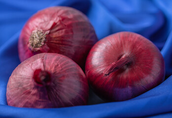 Whole purple fresh onions on blue tablecloth