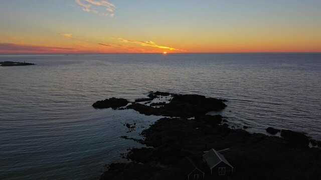 Aerial view of a house on the coast of Gimsoy, midnight sun, in,Lofoten, Norway - descending, drone shot