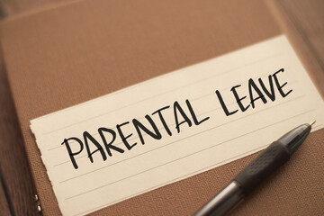 Parental leave, text words typography written on book against wooden background, life and business...