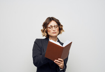 Obraz premium A woman in a suit with a notebook in her hands on a light background work model