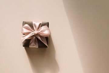 Gift box on beige background with shadows and copy space. Minimal concept.